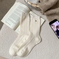 Beige ribbed wool socks with silver pony logo detail in a cozy lifestyle setting - White