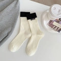 Cream crew socks with black ribbed trim and handmade label in a cozy home setting - One Size / White