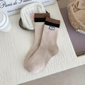 Calcetines de punto beige con rayas marrones y etiqueta de marca en fondo blanco - Talla única / Té con leche