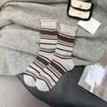 Braune und graue Wollsocken mit Streifen und Rollrand auf herbstlichem Hintergrund - Hellgrau (Grau/Braun Gestreift mit Hellaprikosenkante)