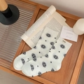Weiße Baumwollsocken mit schwarzen Schneeflocken und Yumy-Label auf Holztablett - Einheitsgröße / Weiß