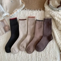 Detailed view of 5 pairs of winter crew socks in earth tones laid on a white fringed rug - One Size / Mixed Colors