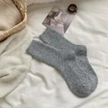 Gemütliche graue Wollstricksocken mit vertikaler Rippenstruktur in Heimkulisse - Hellgrau