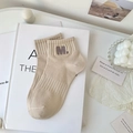 Beigefarbene Baumwollsocken mit lila M-Stickerei auf Kunstbüchern präsentiert - Einheitsgröße / Khaki