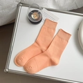 Leuchtend orangefarbene Baumwoll-Stulpen mit Rippbündchen auf weißem Schreibtisch - Einheitsgröße / Orange