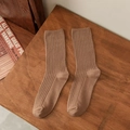 Dames sokken met verticale ribbels in diep kaki op een vintage houten oppervlak - koffiekleur