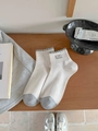 Calcetines de punto crema con volantes grises y parche 'super cute' sobre madera - Talla única / Avena