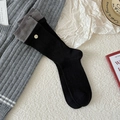 Black ribbed mid-calf socks with grey cuff and decorative button in a cozy setting - Black