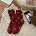 Burgundy wool socks with white bow jacquard pattern in a cozy lifestyle setting - One Size / All-over Bows