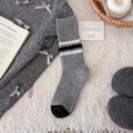 Grey wool blend crew socks with black and white stripes in a cozy home setting - Gray