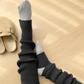 Close-up of black ribbed knit leg warmers showing vertical texture and warm material - One Size / Black