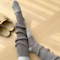 Detailed knit texture of brown ribbed leg warmers paired with grey socks on floor - One Size / Gray