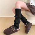 Close-up of black ribbed knit leg warmers paired with fuzzy buckled slides on wood floor - One Size / Black