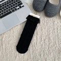 Mid-calf black ribbed socks with elegant lace trim displayed on a cozy plush carpet - Black