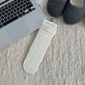 White crew socks with delicate lace trim and cable knit patterns on cozy rug - Beige