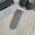 Grey knit mid-calf socks with elegant lace trim and cable texture on cozy rug - Gray