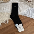 Black ribbed crew socks featuring a delicate gold bow accent on a wooden surface - One Size / Black