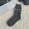 Thick wool socks in dark grey with Nordic snowflake patterns on plush carpet - One Size / Snowflake