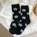 Vintage schwarze Wollsocken mit grauem Blumenmuster auf offenen Buchseiten - Schwarz