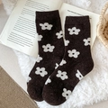 Dunkelbraune Wollsocken mit weißem Blumenmuster auf einem offenen Buch liegend - Kaffeebraun