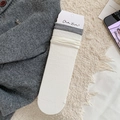 White ribbed cotton mid-calf socks with black striped trim on a soft cream rug - One Size / White