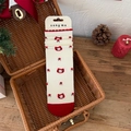 Cream knit mid-calf socks with red cat patterns and floral accents in a festive setting - One Size / Cat
