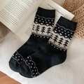 Thick black knitted crew socks with Christmas tree and heart patterns in a cozy setting - One Size / Black