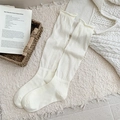 Beige slouch socks with rolled edge and ribbed knit texture in a cozy setting - Creamy White