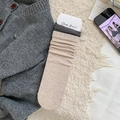 Beige ribbed knit mid-calf socks with black and white striped cuffs in a lifestyle setting - One Size / Khaki