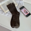 Chaussettes marron foncé mouchetées avec broderie blanche dans une ambiance lifestyle douce - Café