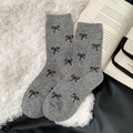 Grey knitted crew socks with black bow patterns on a soft white faux fur background - One Size / Medium Grey