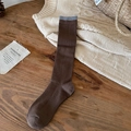 Calcetines de lana café oscuro con borde gris sobre una superficie de madera - café