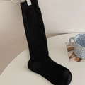 Black ribbed knee-high socks for women made of knit fabric shown on a metal hanger - One Size / Black