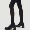 Close-up of black vertical ribbed tights paired with vintage Mary Jane shoes on white background - One Size / Black