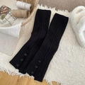 Black ribbed knit leg warmers with side buttons on a textured white cozy rug background - One Size / Black