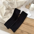 Japanese style black ribbed knit leg warmers laid flat on a rustic wooden table - One Size / Black