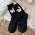 Black wool socks with white plush cat and blue bow design in cozy winter setting - Black
