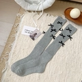 Calcetines grises estilo balletcore con lazos negros sobre alfombra tejida - Gris