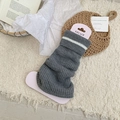 Dark grey knitted leg warmers with white stripe cuff on display card over plush carpet - Gray