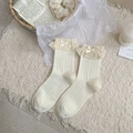 Cremefarbene Wadensocken mit Spitzenbesatz und Satinschleife in ästhetischer Kulisse - Einheitsgröße / Weiß
