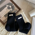 Black ribbed crew socks with a white woven label on a cozy knitted background - One Size / Black