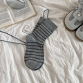 Grey cotton mid-calf socks with black horizontal stripes shown in a cozy home setting - Gray