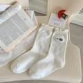 White crew socks with rainbow HAPPY embroidery and ruffled edges on cream chair - White-Letter (Happy)