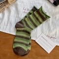 Green and brown striped cotton socks with rolled edges in a cozy home setting - Green Coffee Stripes