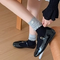 Primer plano de calcetines grises con volantes y botón con zapatos de charol negros - Negro