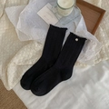 Retro black ribbed crew socks featuring elegant ruffled edges and a silver metal logo detail - One Size / Black