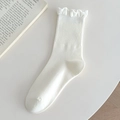 White ribbed cotton crew socks with elegant ruffled edges shown on a white tabletop - White