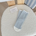 Calze a righe blu chiaro e bianco con dettagli a contrasto su una sedia bianca morbida - Blu