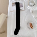 Classic black over-the-knee socks in high-quality knit material laid on white bedding - One Size / Over-knee Black