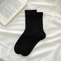 Calcetines negros minimalistas de algodón con puños acanalados sobre fondo de tela blanca - Negro